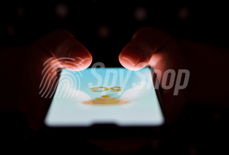 Close-up of the phone screen with 5G network signage. Hands visible above it, the background is dark.