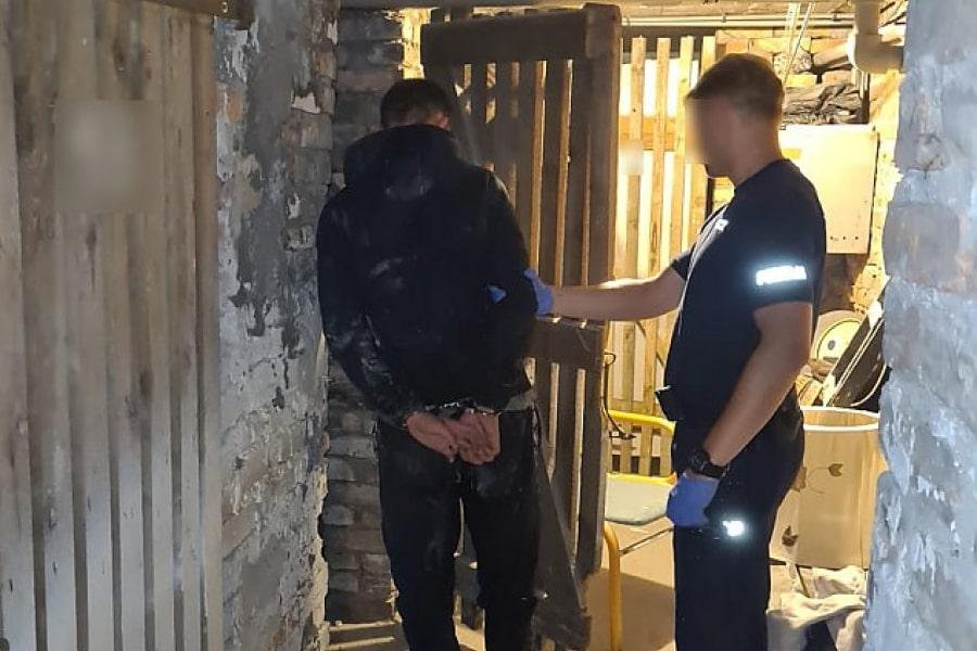 A police officer arresting a handcuffed burglar in a dimly lit basement, highlighting law enforcement efforts to prevent break-ins and theft.