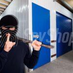 A masked burglar holding a crowbar inside a storage facility, symbolizing the risk of storage unit break-ins and the importance of security measures.
