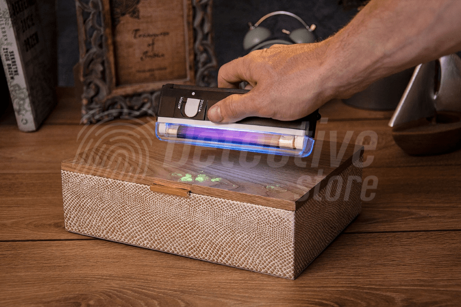 Visible fingerprints under special UV light. The person holds a UV lamp, illuminating the surface on which bright prints appear.