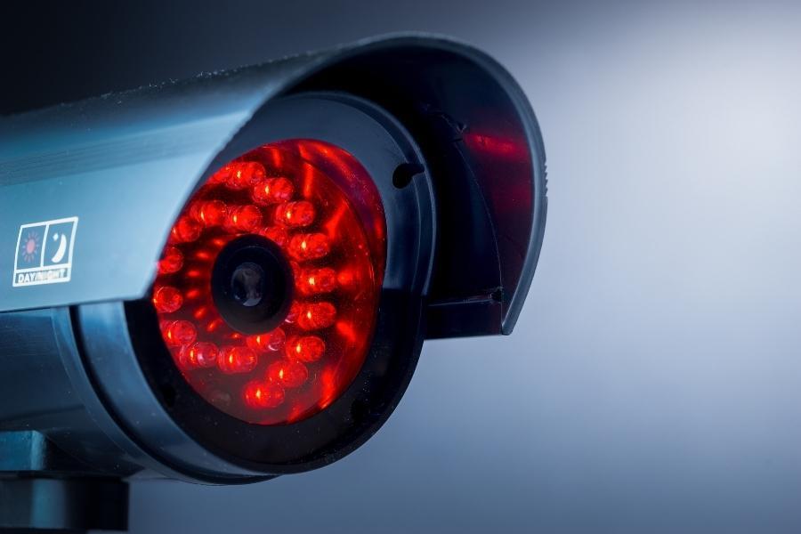 Close-up of a surveillance camera that is recording. Its red LED is lit, indicating that the device is active.