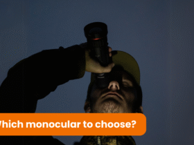 A man wearing a cap is holding a monocular and looking through it into the darkness. It is the middle of the night.