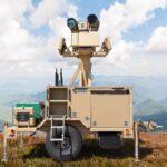المنصة المتنقلة لمكافحة الطائرات بدون طيار مجهزة بأجهزة رادار ومستشعرات بصرية، وتقف على قمة تل أو جبل، مع منظر طبيعي تلالي خلفها.